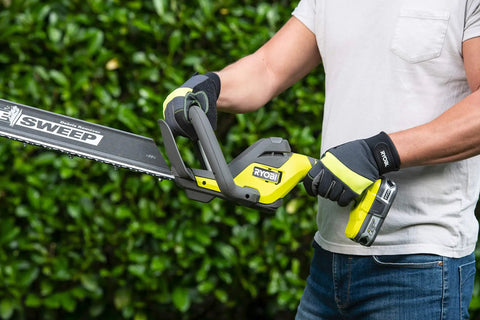 Pro Level 18V ONE PLUS Cordless Hedge Trimmer Featuring 55cm Double Edge Blades And High Output Motor with ergonomic handle in use.