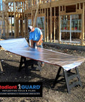 Worker preparing Top Tier Radiant Barrier Attic Insulation Covering 1000 Square Feet with foil at construction site.