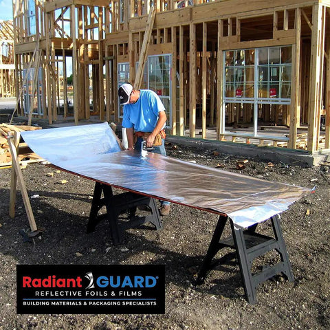 Worker preparing Top Tier Radiant Barrier Attic Insulation Covering 1000 Square Feet with foil at construction site.