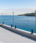 Frameless glass deck railing kit with stainless steel posts overlooking a scenic ocean view, perfect for porch upgrades.