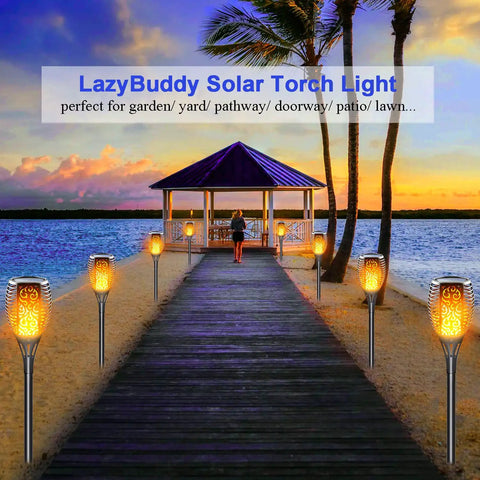 Solar Torch Light With Flickering Flame For Outdoor Yards And Gardens Large IP65 Waterproof Tiki Torches illuminating a walkway.