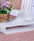 Set Of 50 White Plastic Hangers For Retail Display And Home Closet Organization, stacked on a table with decor