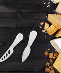 Stainless Steel Cheese Knife Set With Butter Spatulas And Spreaders For Camping And Outdoors next to assorted cheeses.