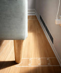 Clear Acrylic Couch Wall Spacers Adjustable Two To Nine Inches Heavy Duty Furniture Stopper placed behind a couch leg.