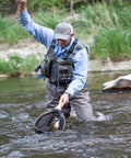 Angler wearing Ultra Lightweight Fly Fishing Vest With 14 Pockets And Front Zip Storage Olive Green in a river catching fish.