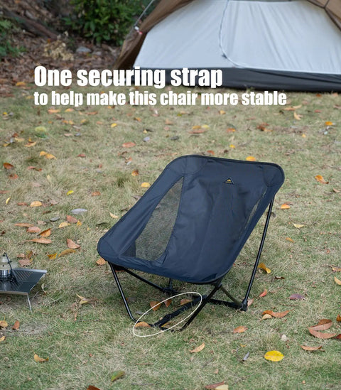 Ultralight Low Profile Camping Folding Chair with side pocket on grass, showing securing strap, ideal for stability on uneven ground.