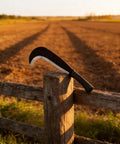 Compact 13.5 Inch Machete Sickle Tool With Curved Blade for Weeding Vine Cutting, rustic setting on wooden fence