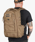 Man wearing MOLLE Compatible Diaper Backpack for Dads With Built-In Changing Mat And Stroller Straps, Rugged 600D Tactical Daypack in Coyote Brown.