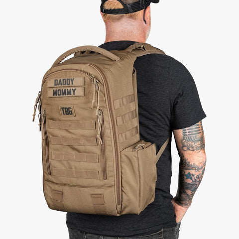Man wearing MOLLE Compatible Diaper Backpack for Dads With Built-In Changing Mat And Stroller Straps, Rugged 600D Tactical Daypack in Coyote Brown.