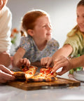 Family enjoying pizza slices together at the table, highlighting the social aspect of meals shared with an indoor pizza oven for home use.