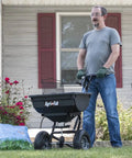 Person using Pro Push Broadcast Spreader 85 Lb Capacity With Durable Plastic Hopper, Corrosion-Resistant And Made In USA for lawn care.