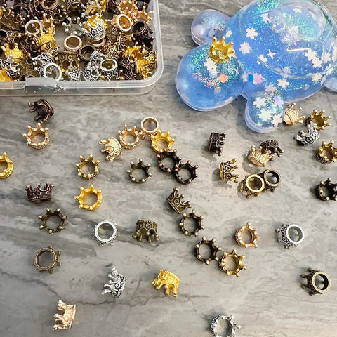 Assortment of 120 Pcs Mini Crown Charms 3D Alloy King Crown Beads Bulk Large Hole Spacer Beads for Jewelry Making on gray surface