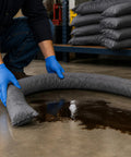 Heavy Duty Universal Absorbent Socks 12 Plus Pack Spill Containment Tubes Industrial Grade Oil Hydraulic Chemical Absorbers Pro Shop Garage Worksite Cleanup Gray being placed around spill.