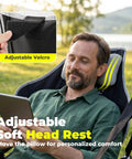 Man relaxing in oversized hammock camping chair with footrest, swing rocker design, adjustable back, headrest with velcro, outdoors.