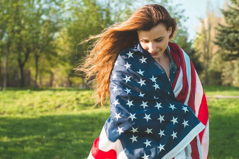 Woman wrapped in Durable Outdoor US Flag 4x6 Ft Built For Weather Heavy Duty 210D Nylon Embroidered Stars Sewn Stripes Brass Grommets