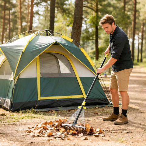 A person using the Go To Adjustable Metal Leaf Rake with Wide and Narrow Modes near a tent, gathering leaves on a camping site.