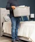 Person holding 40L Laundry Basket With Lightweight Build And Premium Wicker Look Ivory Plastic Hamper in bedroom setting