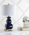 Navy Blue And Gold Ceramic Table Lamp With White Linen Shade on modern footed vase near books and flowers