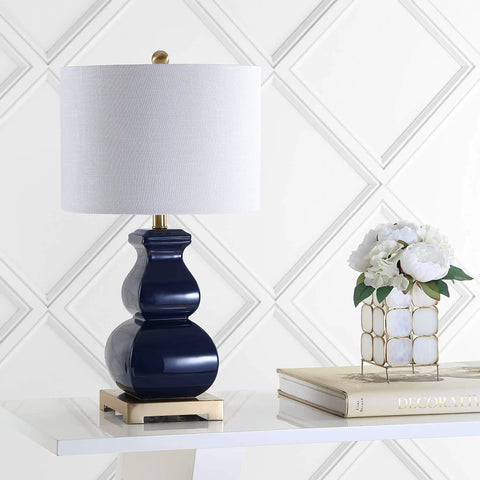 Navy Blue And Gold Ceramic Table Lamp With White Linen Shade on modern footed vase near books and flowers