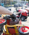 Black nitrile disposable glove on hand adjusting a red workshop machine with a circular grinding wheel