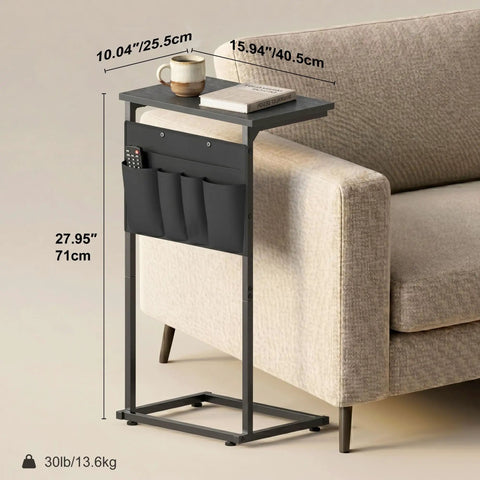 C Shaped End Table With Sliding Tray Under Sofa 28 Inch High Side Table With Storage Bag Black next to a couch with items on top