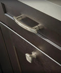 Close-up of Premium Brushed Nickel Cabinet Knobs and handles on dark wooden drawers in a kitchen setting.