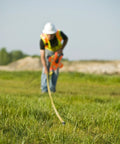 Worker using Hi Viz Orange Fiberglass Tape Measure One Half Inch By Thirty Meters Dual SAE And Metric Readouts on grass site