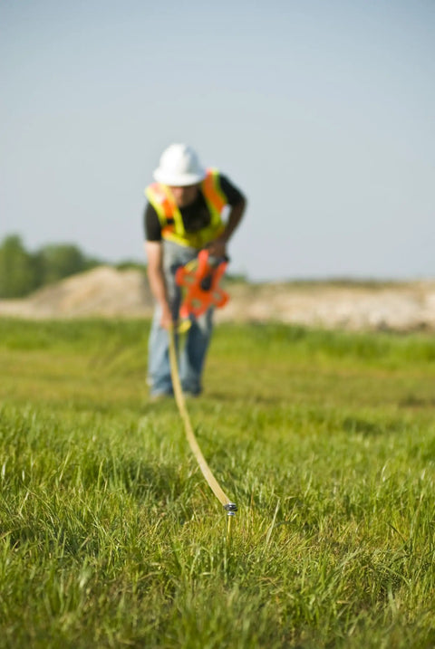 Worker using Hi Viz Orange Fiberglass Tape Measure Half Inch By One Hundred Meters Dual Sided SAE And Metric Tape outdoors