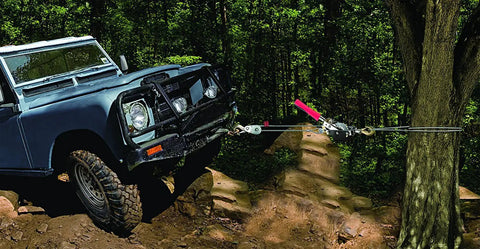 Beefy Compact Power Puller 1 Ton Winch With 6 Ft Aircraft Cable pulling a vehicle uphill in forested terrain