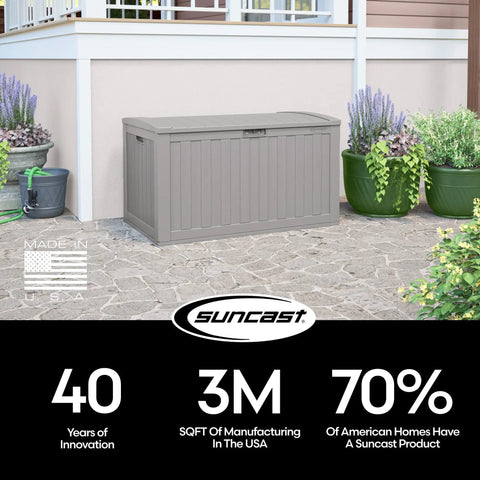 134-Gallon Extra Large Outdoor Deck Box With Pad Lockable Lid against house exterior, grey resin, patio setting.