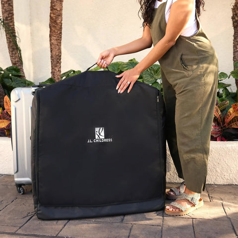 Person holding Universal Stroller Travel Bag For Air Travel, Durable, Padded Go To Case near luggage, outdoor setting