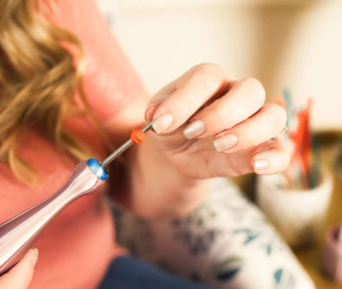 Person using Two Piece Bead Roller Quilling Tool Kit With Slotted Winding Pins In One Eighth Inch And Three Thirty Second Inch Bright Stainless Steel Pink Pearl Silk Handle For Paper Jewelry Making to create paper jewelry.