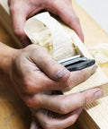 Close-up of hands using Pro Grade Japanese Kanna Pull Plane Hitachi Aogami Blue Steel Number Two Blade on oak wood.