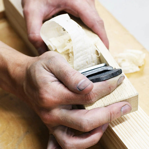 Close-up of hands using Pro Grade Japanese Kanna Pull Plane Hitachi Aogami Blue Steel Number Two Blade on oak wood.