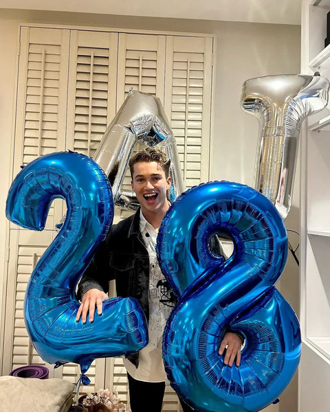 Person holding Deep Navy Blue Number 2 Balloon, 40 Inch Giant Digit Balloon For Birthday Backdrop alongside other digit balloons.