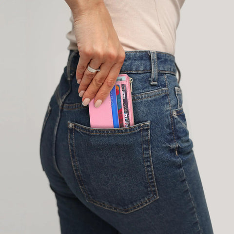 Woman putting Slim RFID Blocking Wallet For Women With Front Pocket Card Case, 6 Card Slots, ID Window in chic pink into jeans pocket