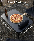 Ultra Portable Camping Table With Aluminum Frame holding pizza, speaker, and drink, outdoor setting, 60 cm by 40 cm size.