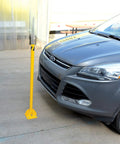 Tough As Nails Ground Mount Heavy Duty Steel Fold Down Bollard Padlock Secured Parking Lot Barrier Yellow Galvanized safety post near parked car