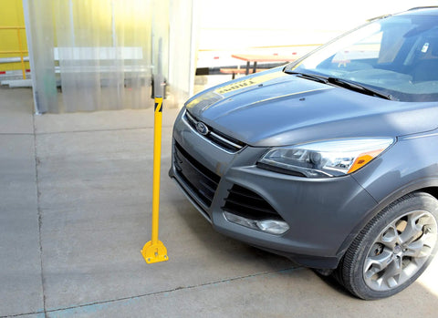 Tough As Nails Ground Mount Heavy Duty Steel Fold Down Bollard Padlock Secured Parking Lot Barrier Yellow Galvanized safety post near parked car