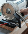 BG-GRIND4 4-piece grinding jig set for wood chisels, mounted on a bench grinder with a chisel in the jig