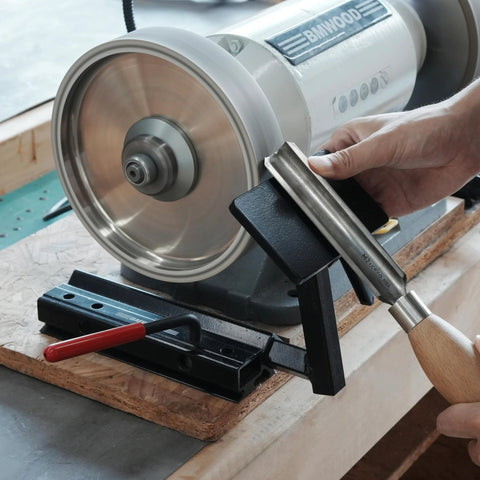 BG-GRIND4 4-piece grinding jig set for wood chisels, mounted on a bench grinder with a chisel in the jig