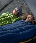 Two adults relaxing in Ultralight RDS Down Sleeping Bags for Adults, 650 Fill Power, zipped together in a tent.