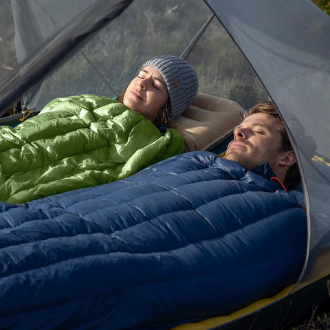 Two adults relaxing in Ultralight RDS Down Sleeping Bags for Adults, 650 Fill Power, zipped together in a tent.