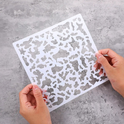Hands holding an 8x8 inch stencil from the Six Pack Knockdown Texture Spray Stencil Kit for Drywall Repair and Plaster Walls