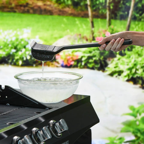 Steam Activated Grill Brush With ArmorTec Bristle Free Mesh Powered By Scrub Daddy shown being dipped in water near a grill