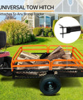 Beefy ATV Dump Cart With 1500 Lbs Capacity attached to tractor, transporting firewood on lawn, showing universal tow hitch.