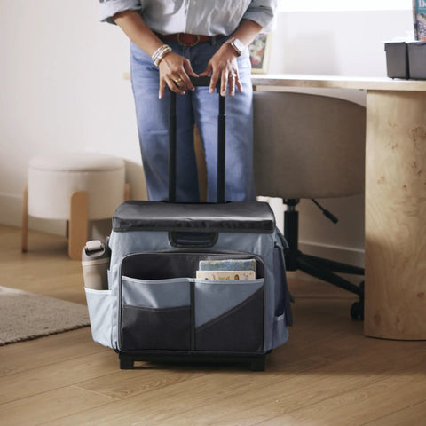 Person holding foldable utility cart with canvas organizer bag and removable saddlebag, black and grey, next to office desk