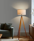 Eden Tripod Floor Lamp Dimmable LED With Solid Wood Legs in modern living room setting, tall tree style lamp next to sofa.