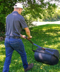 Person using powerful 270 lb poly lawn roller for push or tow with easy turn tethered plug and quick filling drum in garden