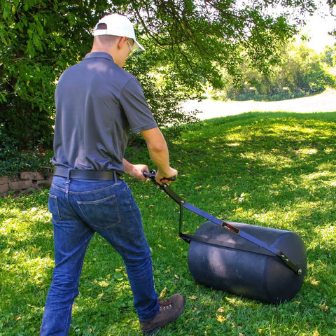 Person using 270 Lb Push And Tow Poly Lawn Roller With Easy Turn Tethered Plug 18 By 24 Inch Flat Black Heavy Duty Drum